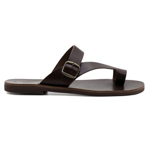 May include: Brown leather sandals with a buckle strap and a toe loop. The sandals have a flat sole.