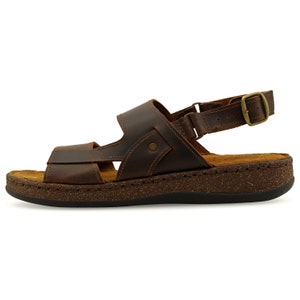 May include: Brown leather sandals with a buckle strap and a cork platform sole.