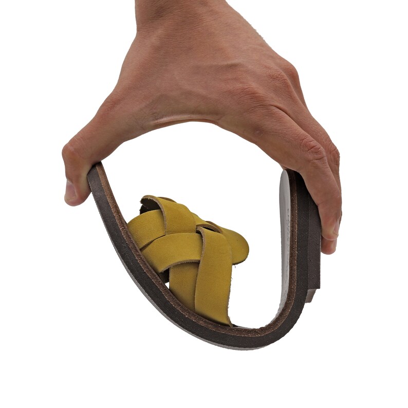May include: A pair of yellow leather sandals with a woven design. The sandals have a brown leather sole.