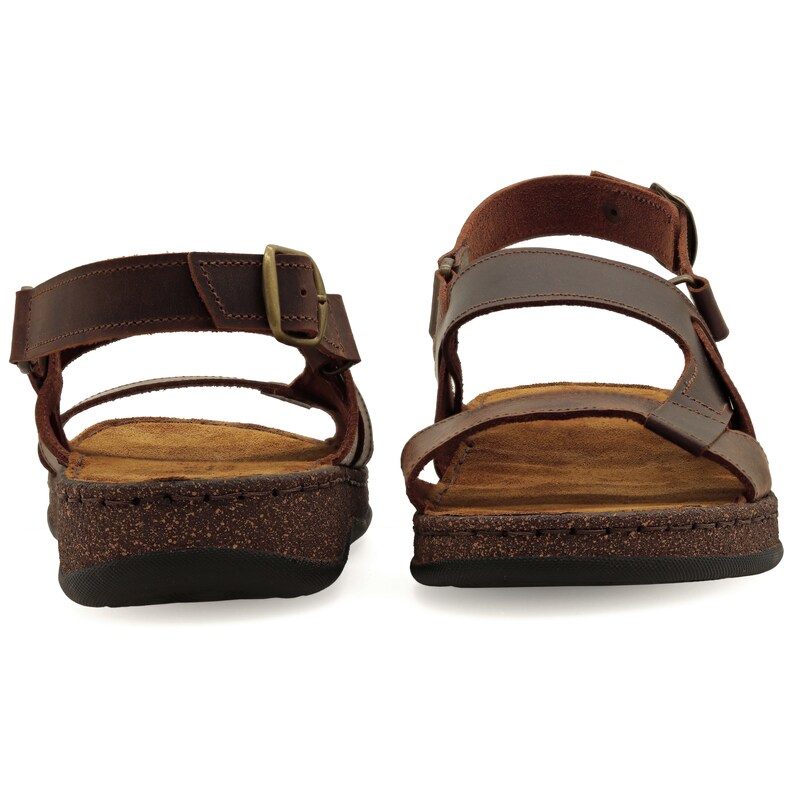 May include: A pair of brown leather sandals with a buckle closure. The sandals have a cork footbed and a brown rubber outsole.