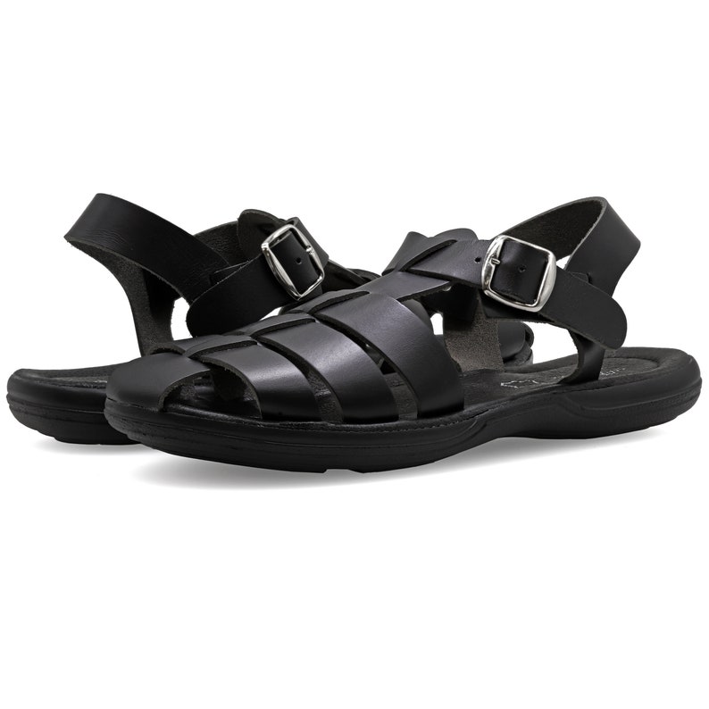 Op de afbeelding: Zwarte leren sandalen met een gespsluiting en een geweven ontwerp. De sandalen hebben een comfortabel, gepolsterd voetbed.