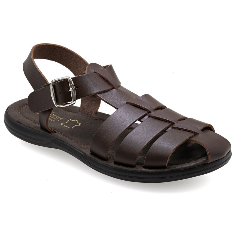 May include: Brown leather sandal with a woven design across the top. The sandal features a buckle closure and a black sole. The sandal is designed for comfort and style, suitable for casual wear.