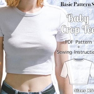 May include: A white short-sleeved crop top t-shirt. The image includes text reading Basic Pattern Shop, Baby Crop Tee, PDF Pattern + Sewing Instructions, and Sizes XS-4XL, alongside a black and white line drawing of the crop top.