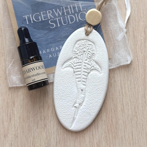 May include: A white ceramic mug with a black handle and the text "But First, Coffee" in a bold, black font. The mug is filled with a dark liquid, likely coffee, and rests on a light-coloured surface.