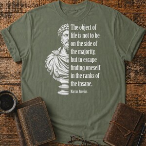 May include: An olive green t-shirt featuring a white graphic of a Marcus Aurelius bust on the left and the text: The object of life is not to be on the side of the majority, but to escape finding oneself in the ranks of the insane. Marcus Aurelius.