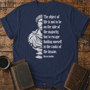 May include: A navy blue t-shirt featuring a white graphic of a Marcus Aurelius bust on the left side and the quote: The object of life is not to be on the side of the majority, but to escape finding oneself in the ranks of the insane. Marcus Aurelius.