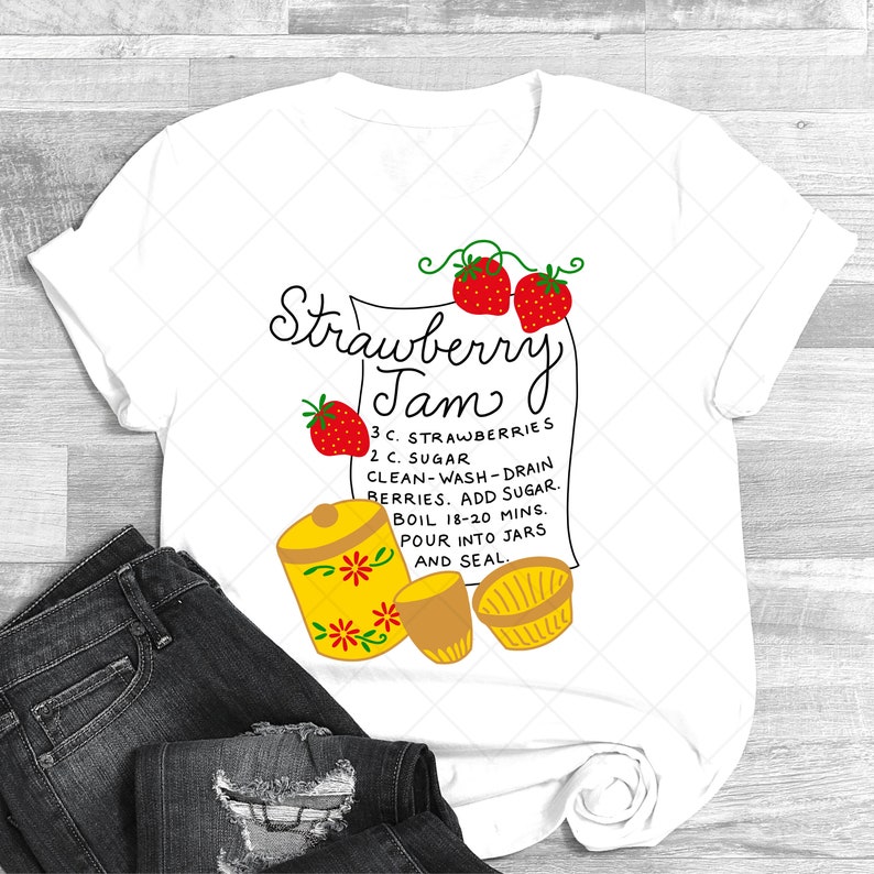 May include: White t-shirt with a red and green illustration of strawberries and a yellow jar with flowers. The text reads "Strawberry Jam" and includes a recipe for making strawberry jam.