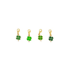 May include: Four gold-tone charms with green four-leaf clover designs. Each charm has a lobster clasp.