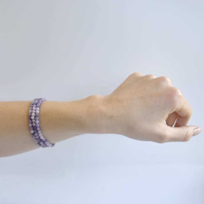 Puede incluir: Un brazalete de triple vuelta hecho de peque&ntilde;as cuentas redondas de color lavanda.