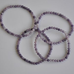Puede incluir: Cuatro pulseras de piedras preciosas moradas hechas de peque&ntilde;as cuentas redondas.