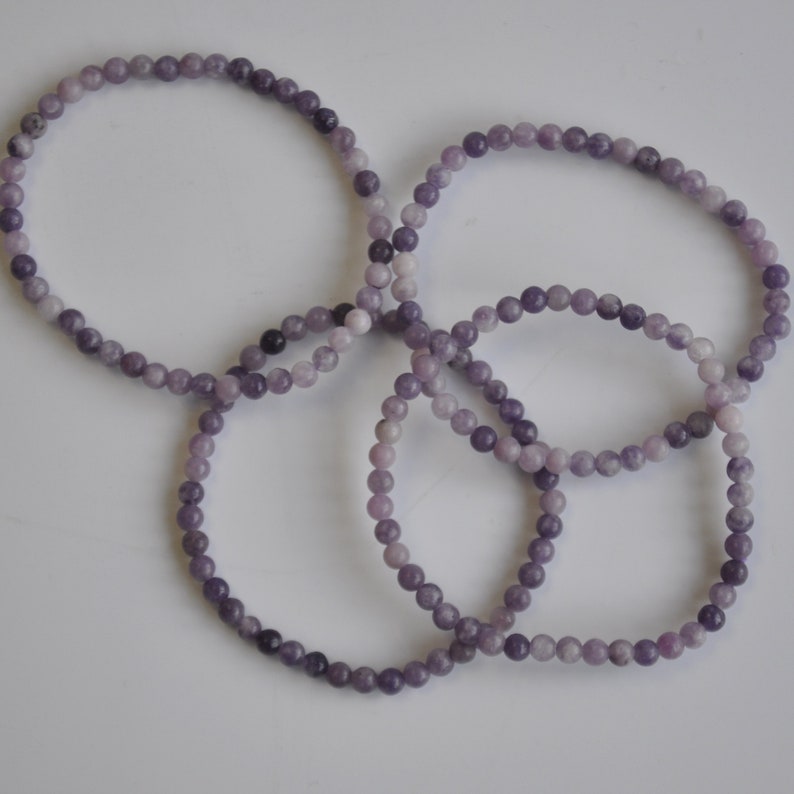 Puede incluir: Cuatro pulseras de piedras preciosas moradas hechas de peque&ntilde;as cuentas redondas.