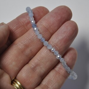 May include: A delicate bracelet made with light blue gemstone beads. The beads are faceted and have a subtle shimmer.