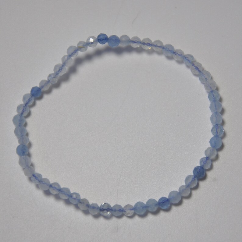 May include: A delicate bracelet made of light blue gemstone beads. The beads are faceted and have a subtle shimmer.