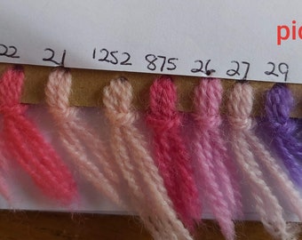 May include: A yarn color chart with 11 different shades of pink, purple, and blue yarn. The yarn is labeled with numbers: 1012, 23, 22, 21, 1252, 875, 26, 27, 29, 28, 103.