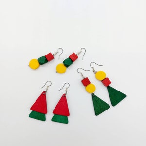 May include: A set of four pairs of earrings featuring geometric shapes and bright colors. The earrings are made of wood and have a red, yellow, and green color scheme.