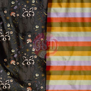Peut inclure: Tissu noir avec un motif répété de ratons laveurs, de fleurs et d'étoiles. Le tissu est à côté d'un tissu rayé avec des rayures orange, jaunes, vertes et violettes.