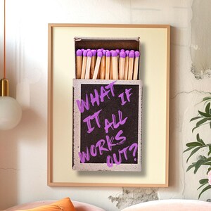 May include: A framed print of a matchbox with the text "WHAT IF IT ALL WORKS OUT?" written in purple on the side. The matchbox is filled with matches with purple heads.