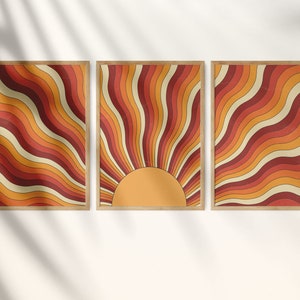 May include: Three framed prints with a retro sunburst design. The sunburst is made up of orange, red, and yellow wavy lines. The center of the sunburst is a solid yellow circle.