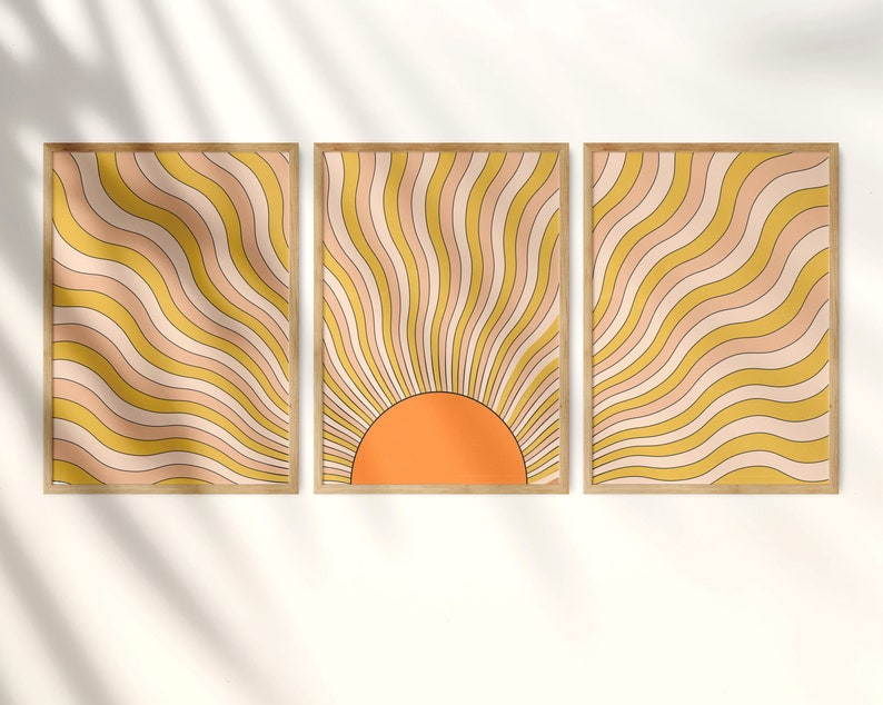 May include: Three framed prints with a retro sunburst design. The prints feature a yellow and orange color scheme with wavy lines radiating from a central orange circle.