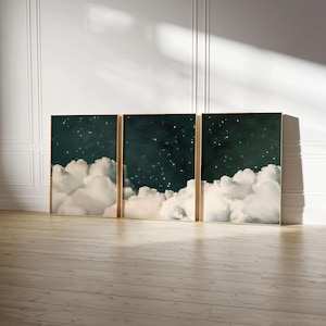 Puede incluir: Tres impresiones artísticas enmarcadas que representan una escena de cielo nocturno con nubes blancas y esponjosas y un fondo verde oscuro. La obra de arte tiene un marco dorado y se exhibe sobre un suelo de madera.
