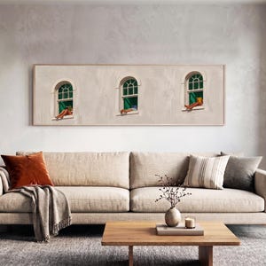 Pode incluir: Uma peça de arte de parede retangular horizontal emoldurada, apresentando uma fachada de edifício de cor clara com três janelas em arco. Cada janela exibe uma moldura verde e uma pessoa descansando no parapeito, com pernas e pés visíveis.