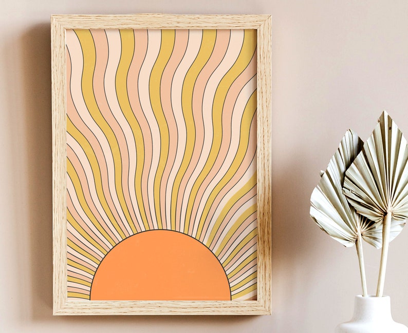 May include: A framed print of a retro sunburst design with a yellow, orange, and pink color scheme. The sunburst is made up of wavy lines that radiate outward from a central orange circle.