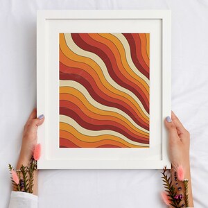 May include: A framed print with a retro abstract design featuring wavy lines in shades of orange, red, and cream.