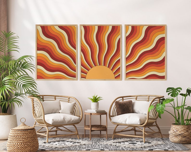 May include: Three framed prints of a retro sunburst design in shades of orange, red, and yellow. The sunburst design is made up of wavy lines.