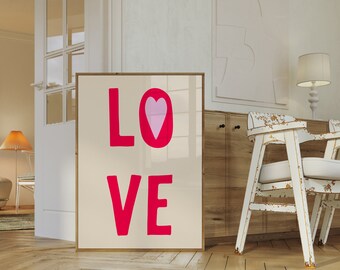 Puede incluir: Una impresión enmarcada con la palabra "LOVE" en letras grandes de color rosa. Un corazón rosa está centrado sobre la palabra "LOVE". La impresión está sobre un fondo crema y está enmarcada en un marco de madera claro.