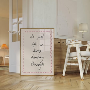 May include: A white poster with a pink border and the text "its just life so keep dancing through" written in black cursive.
