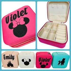 May include: Four pink, white, blue and turquoise jewelry boxes with different designs. The boxes have a zipper closure and are decorated with a Disney character, a castle, and a name. The boxes are open to show the interior compartments.