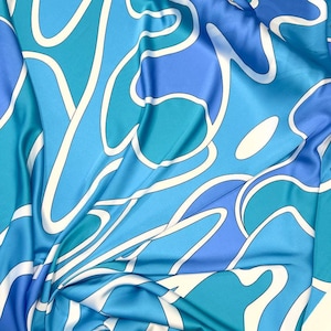 May include: A blue, green and white patterned fabric with a flowing, abstract design. The fabric is made of a silky material and has a smooth texture.