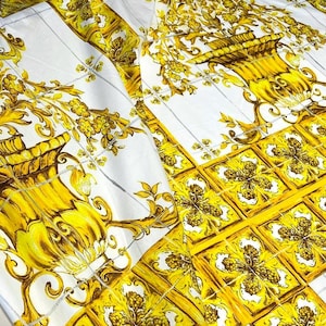 May include: White fabric with a yellow and brown floral pattern. The pattern features a repeating design of stylized flowers and leaves in a vase.