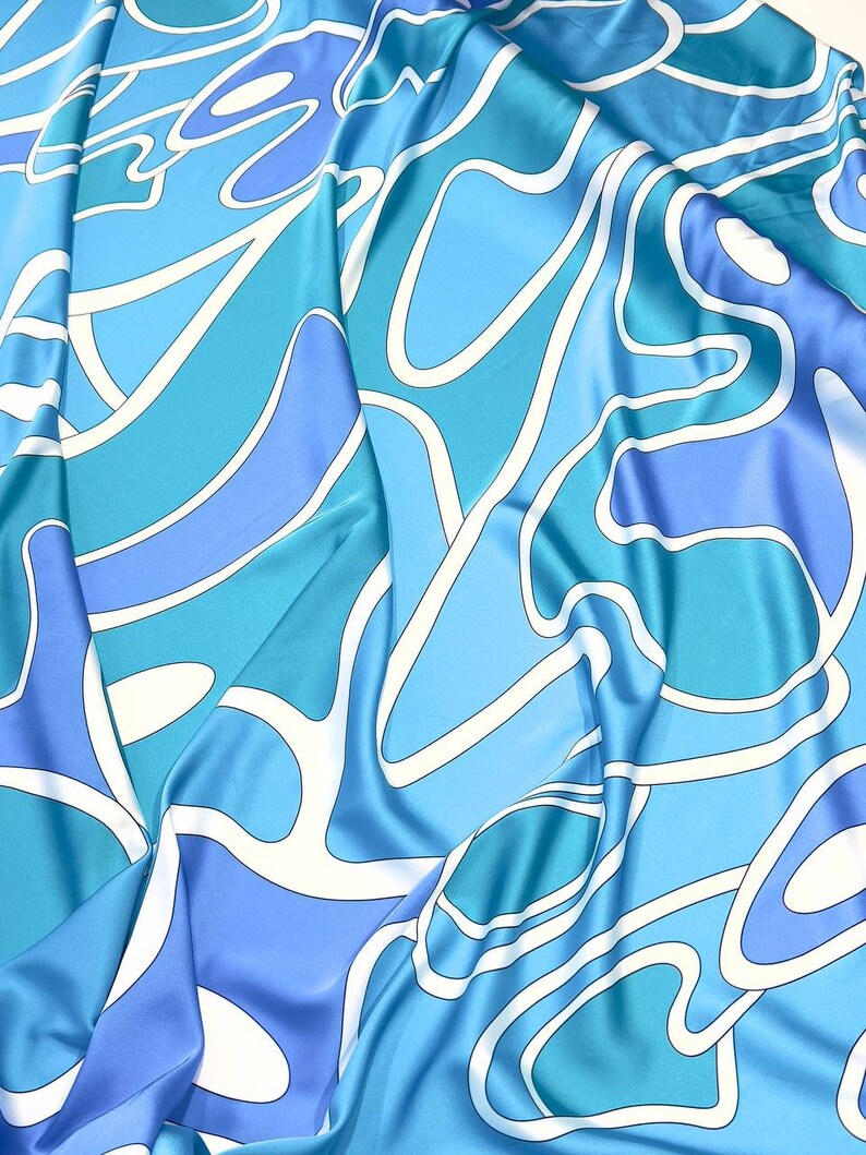 May include: Blue and white abstract patterned fabric with a silky texture.