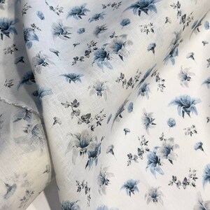 May include: White fabric with a blue floral pattern. The fabric is folded in half and the pattern is visible on both sides.
