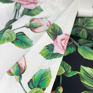 May include: Two fabric swatches with a floral pattern. One swatch is white with pink roses and green leaves. The other swatch is black with pink roses and green leaves.