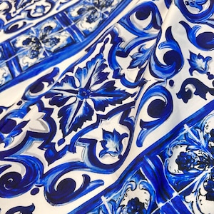 Può includere: Tessuto a motivi blu e bianchi con un design a piastrelle ripetuto. Il tessuto ha una texture liscia e setosa.