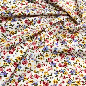 May include: White fabric with a small floral print in shades of pink, yellow, blue, and green.