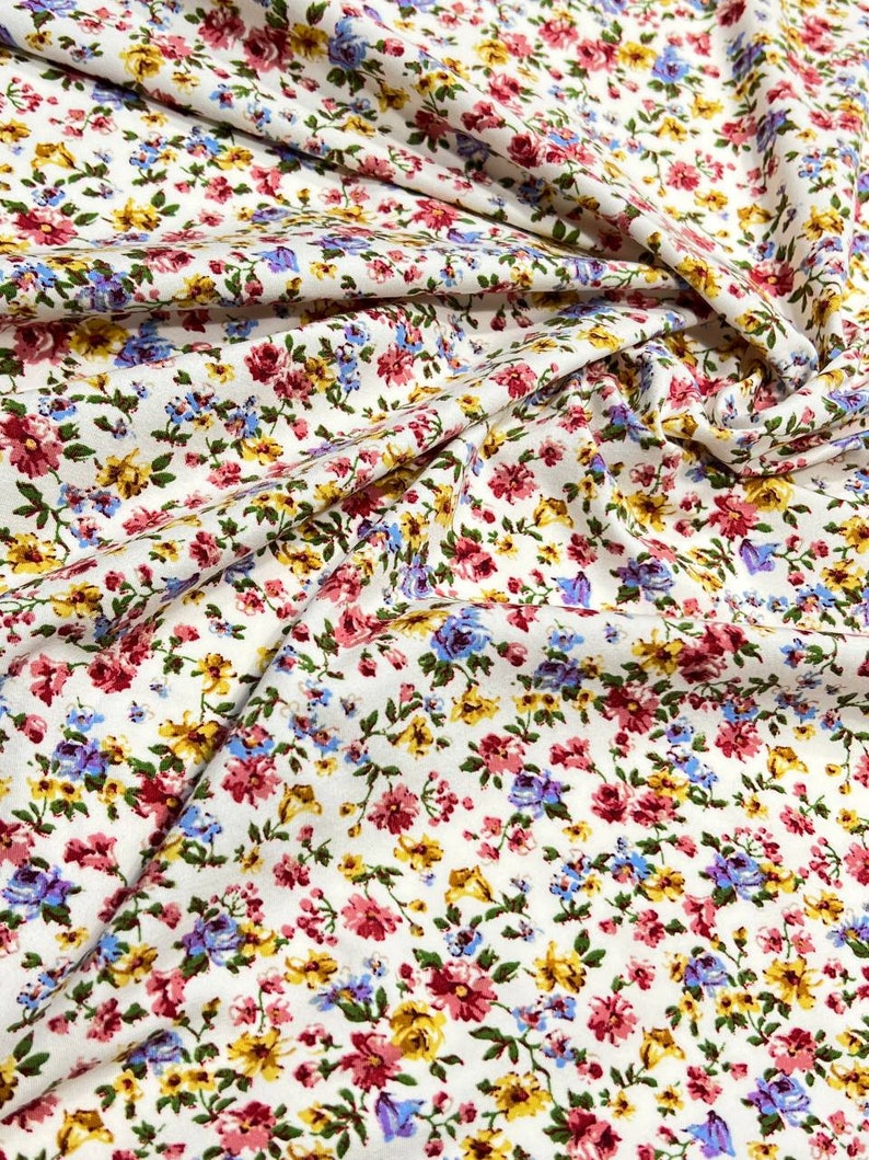 May include: White fabric with a small floral print in shades of pink, yellow, blue, and green.