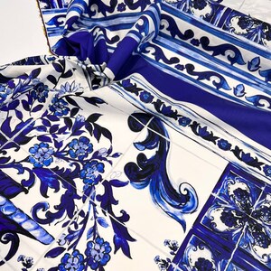 May include: Blue and white patterned fabric with a floral design. The fabric features a repeating pattern of blue and white tiles with floral motifs.