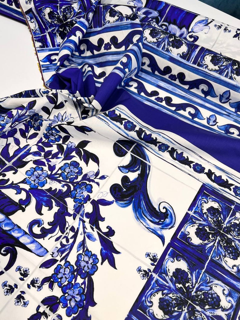 May include: Blue and white patterned fabric with a floral design. The fabric features a repeating pattern of blue and white tiles with floral motifs.