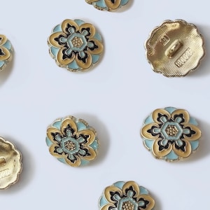 May include: Assortment of gold-tone buttons with a blue and black floral design. The buttons have a raised, textured surface and a shiny finish.