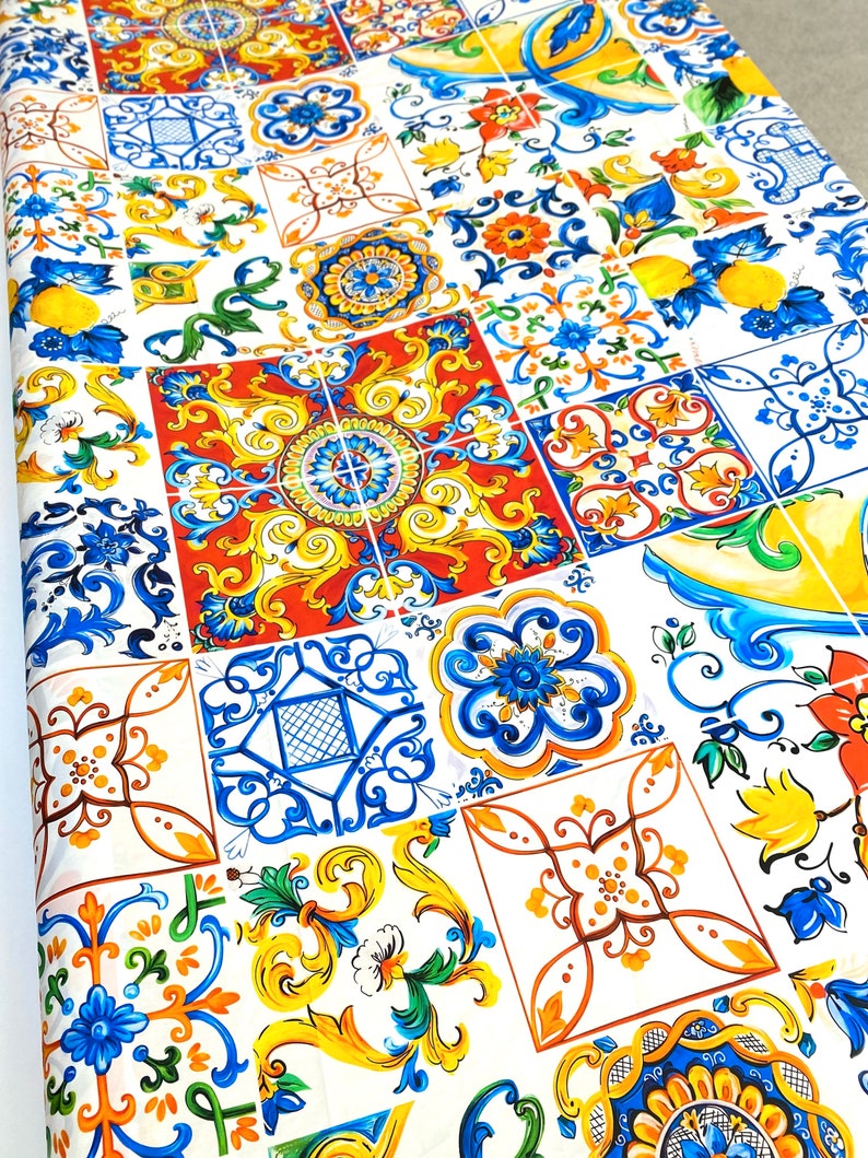 Pu&ograve; includere: Un tessuto bianco con un motivo ripetuto di piastrelle geometriche colorate. Le piastrelle sono in tonalit&agrave; di blu, giallo, rosso e verde e presentano intricati disegni floreali.