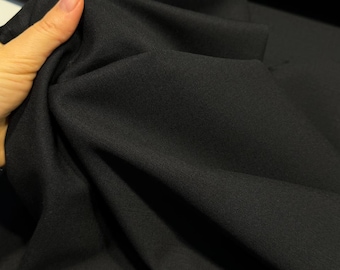 May include: Black fabric with a smooth, woven texture. The fabric is folded and draped, showing its soft, drapey quality.