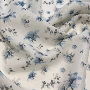 May include: White linen fabric with a blue floral pattern. The fabric is soft and has a subtle sheen.