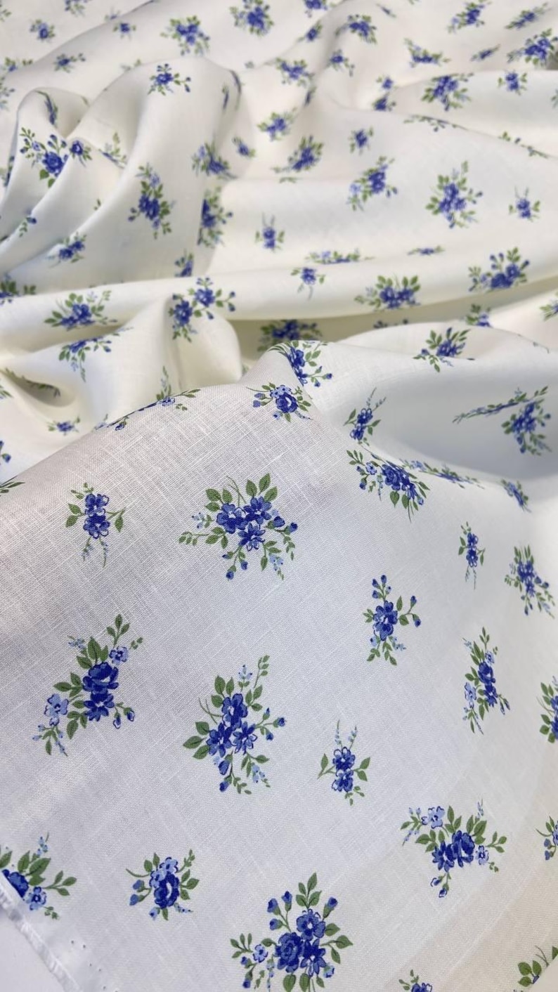 Pu&ograve; includere: Tessuto bianco con un piccolo motivo floreale blu. Il tessuto ha una trama di lino.