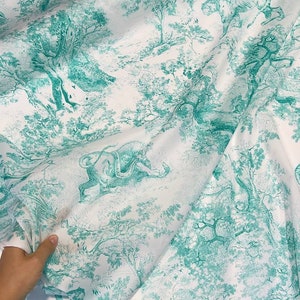 May include: White fabric with a teal toile de Jouy pattern. The design features detailed illustrations of trees, tigers, and other animals in a forest setting. The fabric is folded, showing the pattern's repeat.