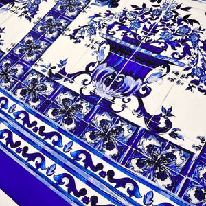 May include: Blue and white patterned fabric with a repeating design of flowers and a vase. The fabric has a blue border with a white and blue pattern.