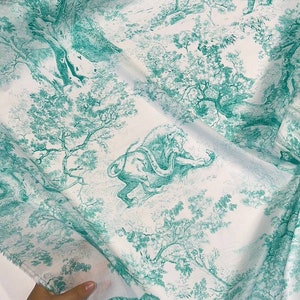 May include: White fabric with a teal toile pattern featuring tigers, lions, and trees. The fabric is folded, revealing the detailed illustration of a jungle scene. The design is reminiscent of classic toile de Jouy.