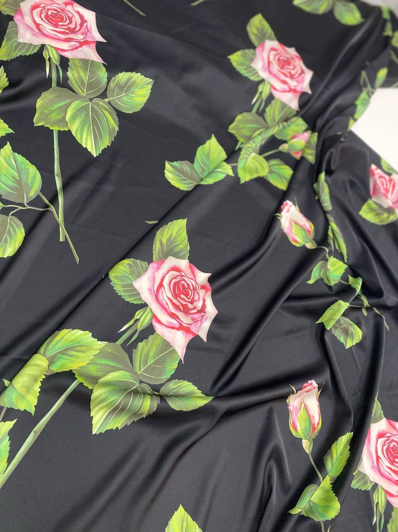 May include: Black satin fabric with a repeating pattern of pink and white roses with green leaves.